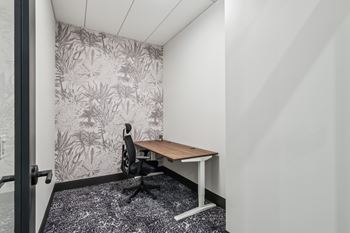 A small room with a desk and a plant pattern wallpaper at LiveWell Apartments, Pittsburgh, PA, 15222